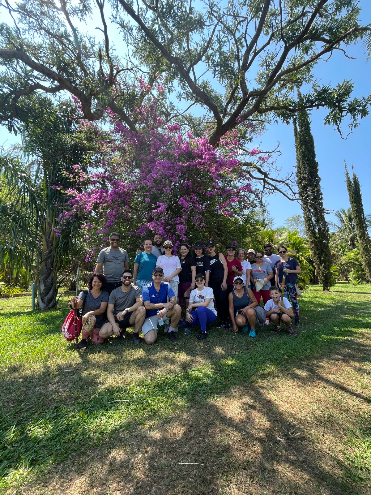 Imagem mostra os participantes da Caminhada Ecológica em meio a natureza, conhecendo o Campus Glória e registrando fotos da atividade. 