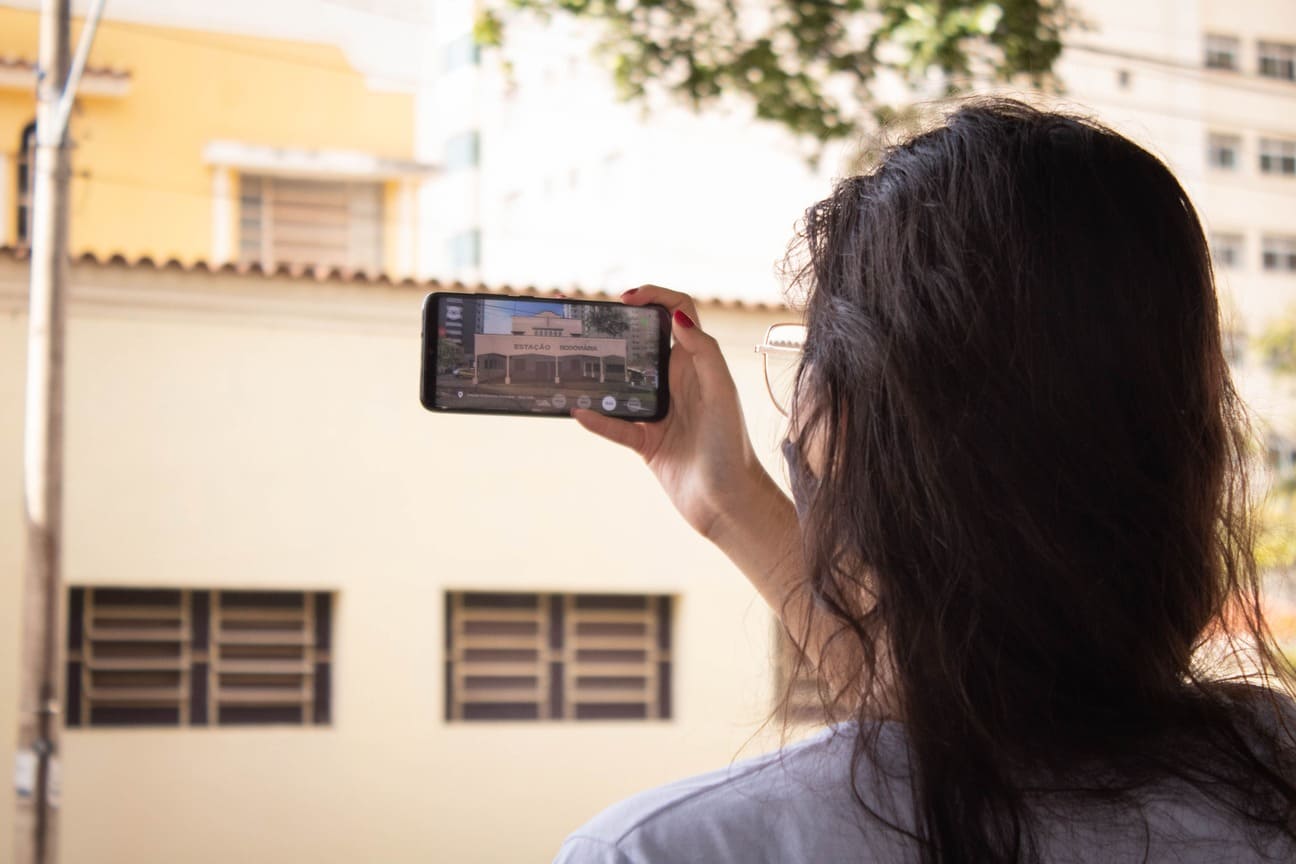  Mulher apontando a câmera do celular para um edifício 