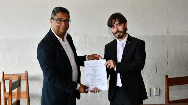 Imagem do pró-reitor Hélder Silveira (à esquerda) e do delegado Anderson Luiz da Silva exibindo o documento de doação dos materiais 