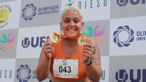 Atleta mulher segurando duas medalhas de ouro