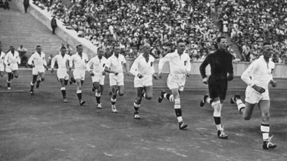 Imagem em preto e branco, jogadores do time de handebol da Alemanha em 1936, em fila.