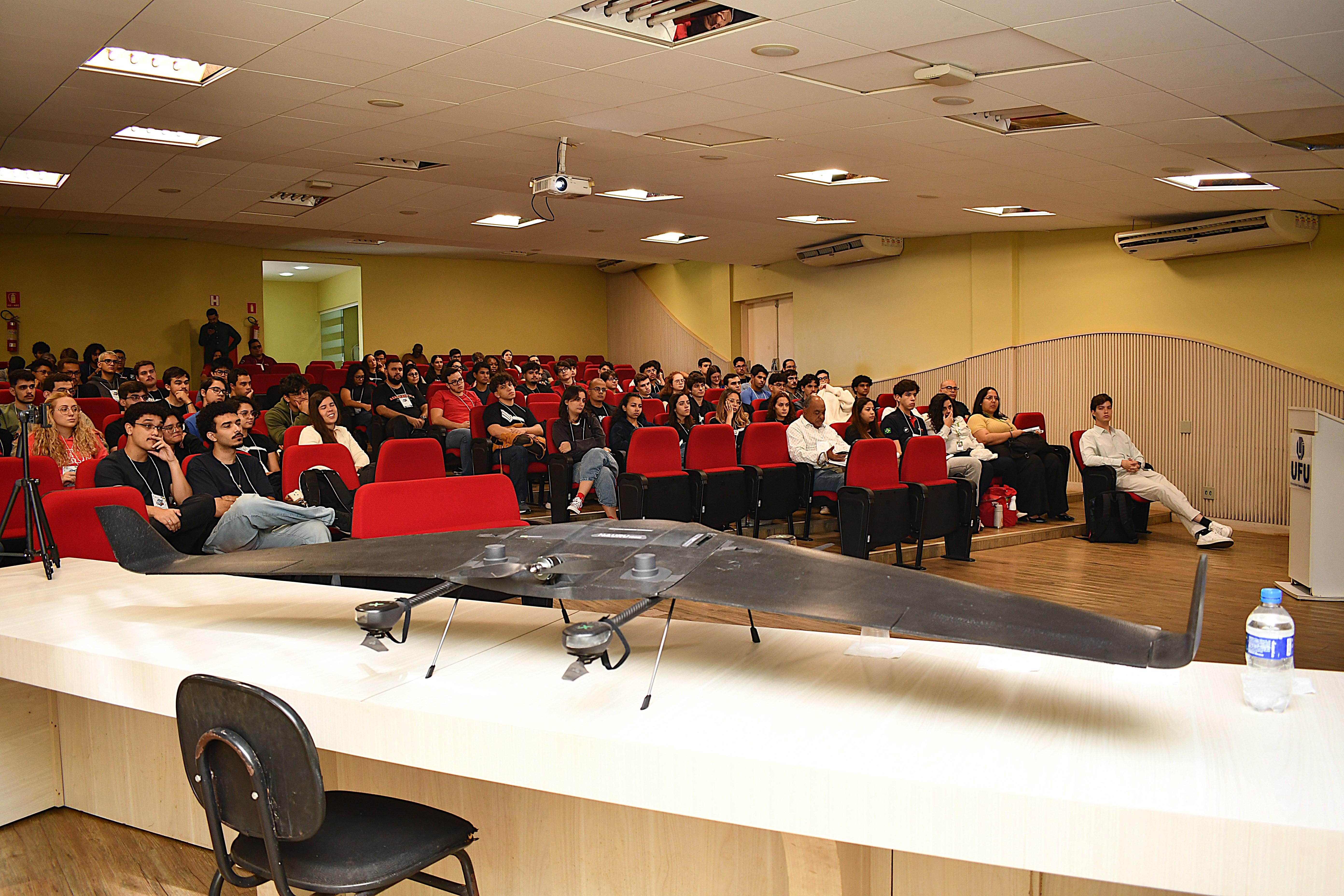 Foto da apresentação com um modelo aeronautico exposto para os estudantes