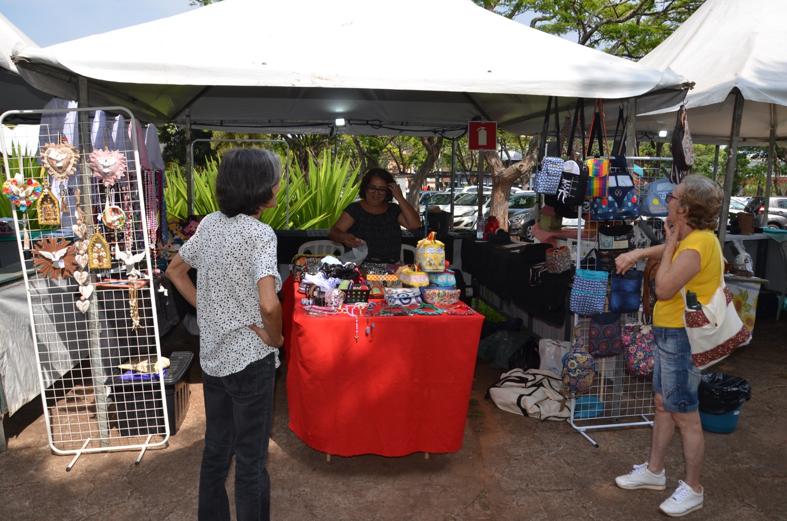 Barraca de artesanato com mulheres escolhendo seus produtos.