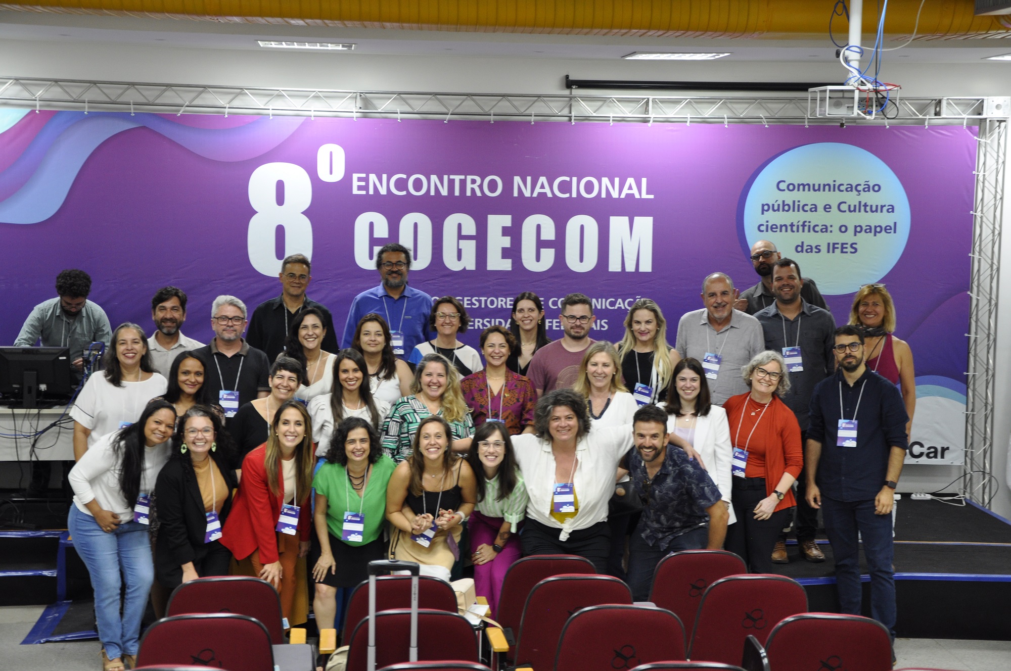 Participantes do 8º Congresso Nacional Cogecom posam em frente ao backdrop do evento