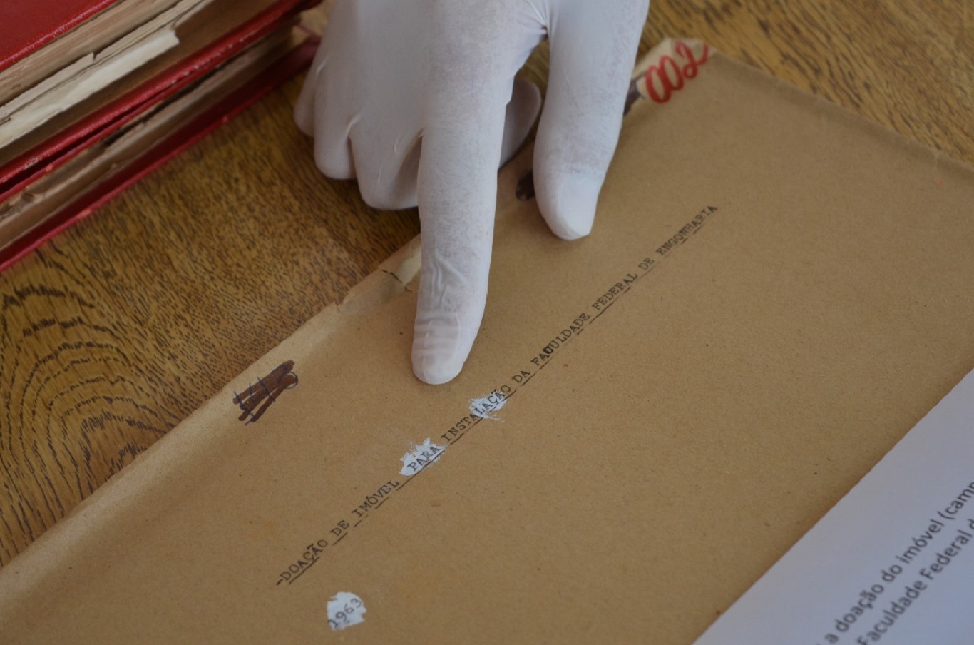 Imagem detalhe de um documento com a ponta do dedo indicador de um arquivista indicando o escrito
