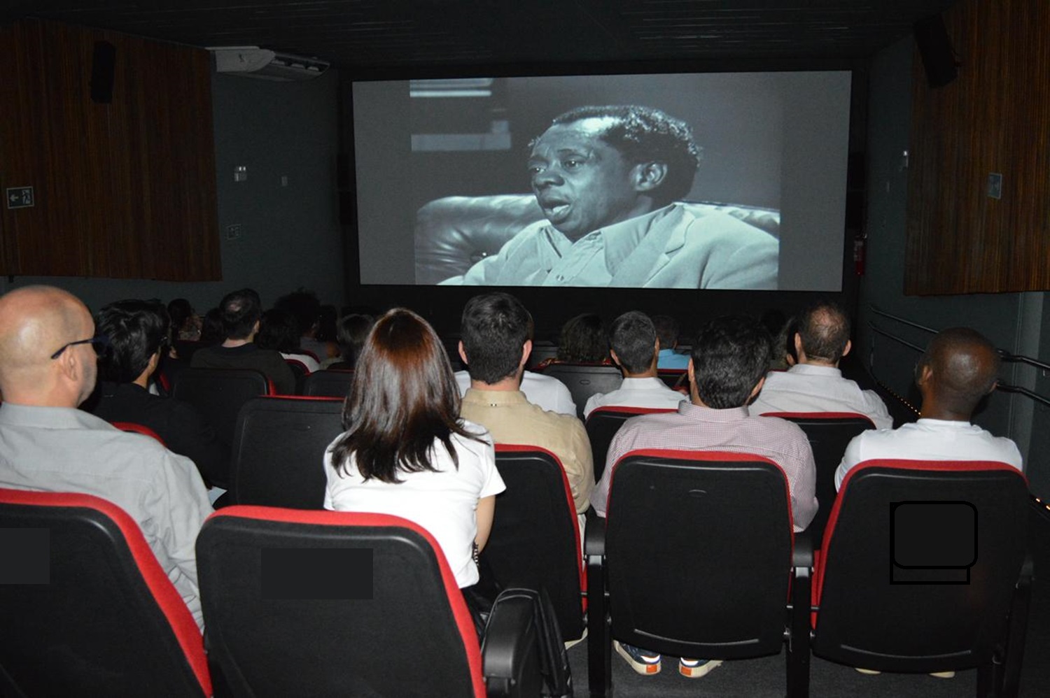 pessoas assinstindo o filme do grande otelo no cinema