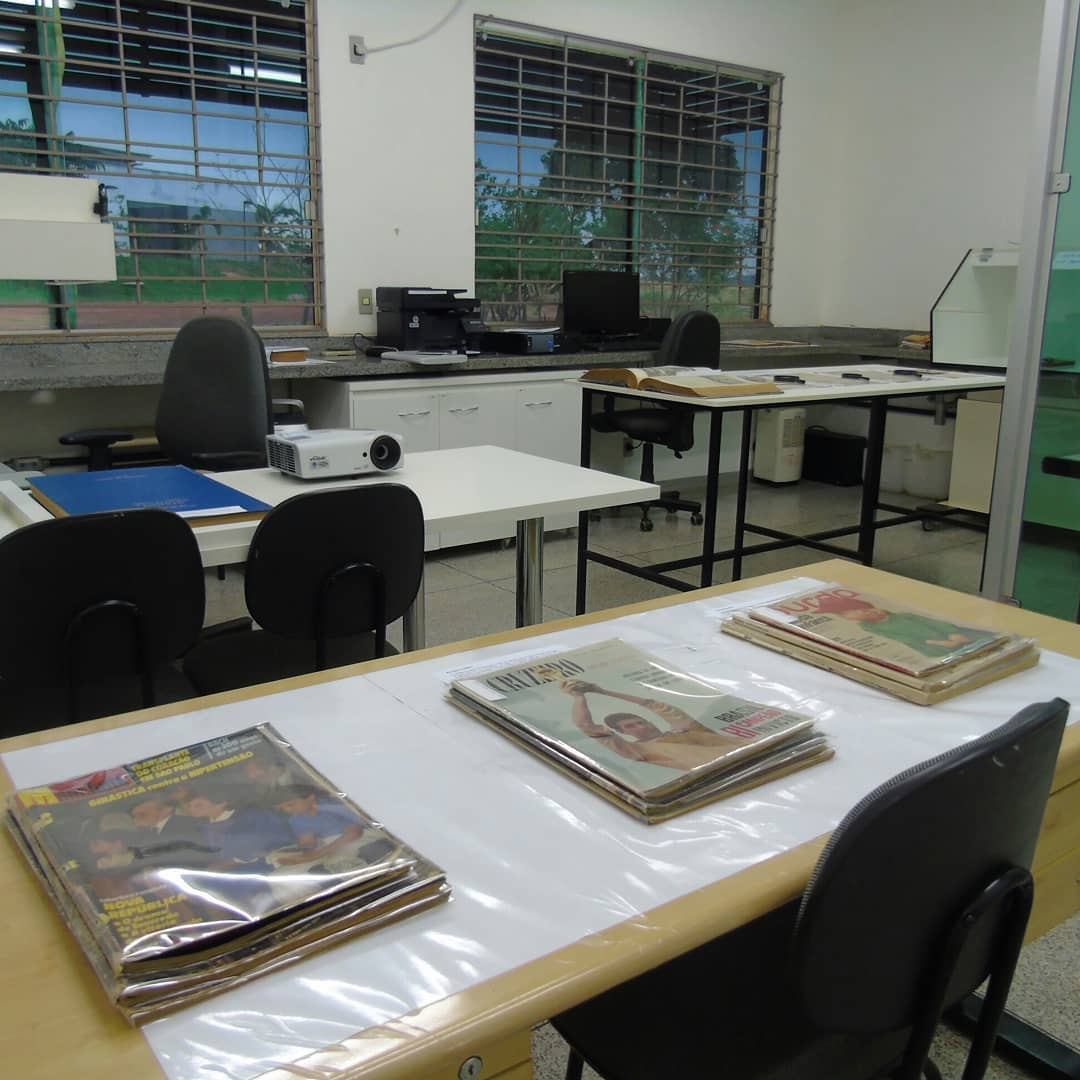 Espaço físico do Centro de Pesquisa, Documentação e Memória do Pontal mostra arquivos expostos sobre a mesa e cadeira em volta