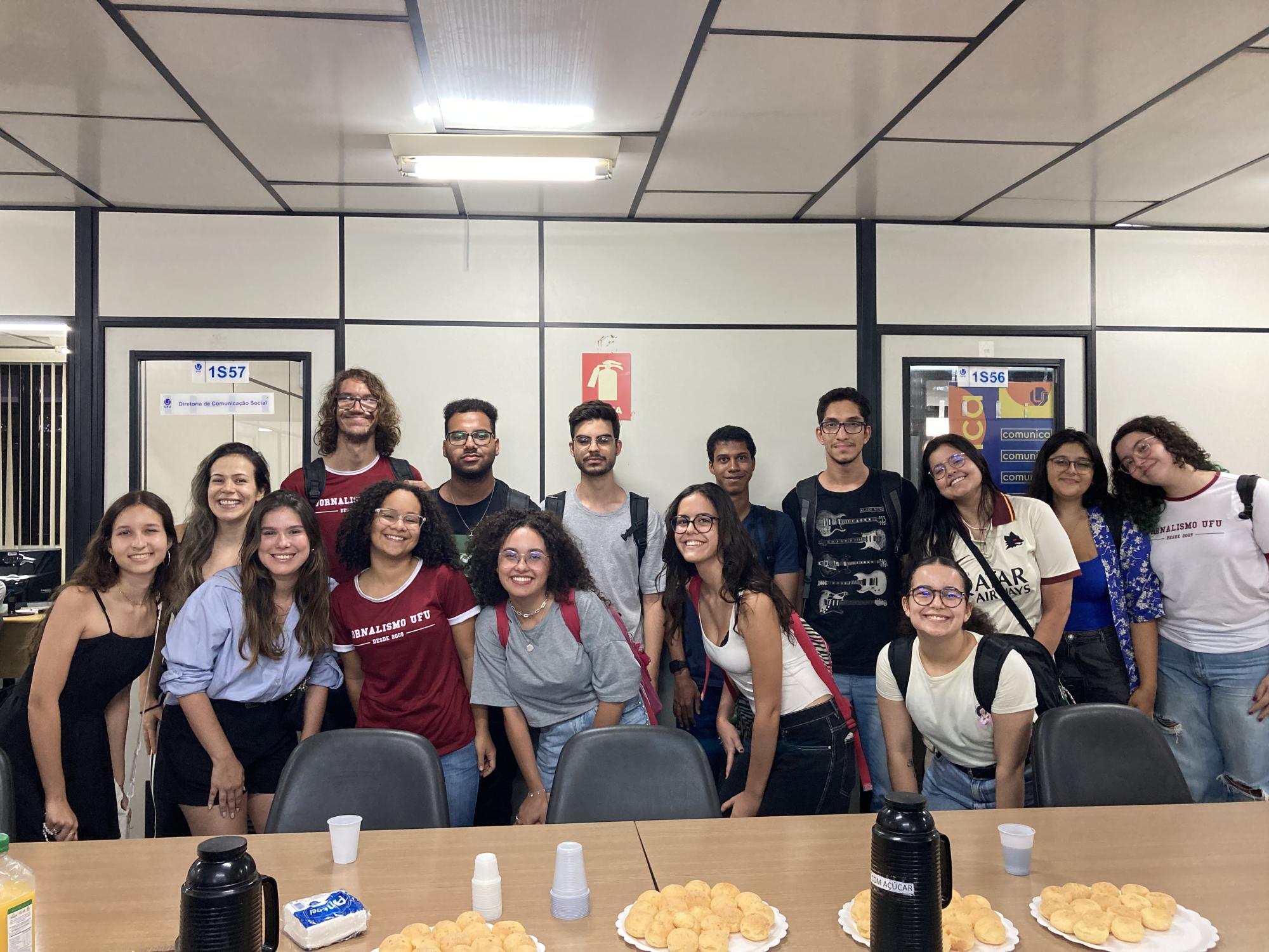 Na imagem, diversas pessoas reunidas atrás de uma mesa com o fundo branco; e todas estão sorrindo