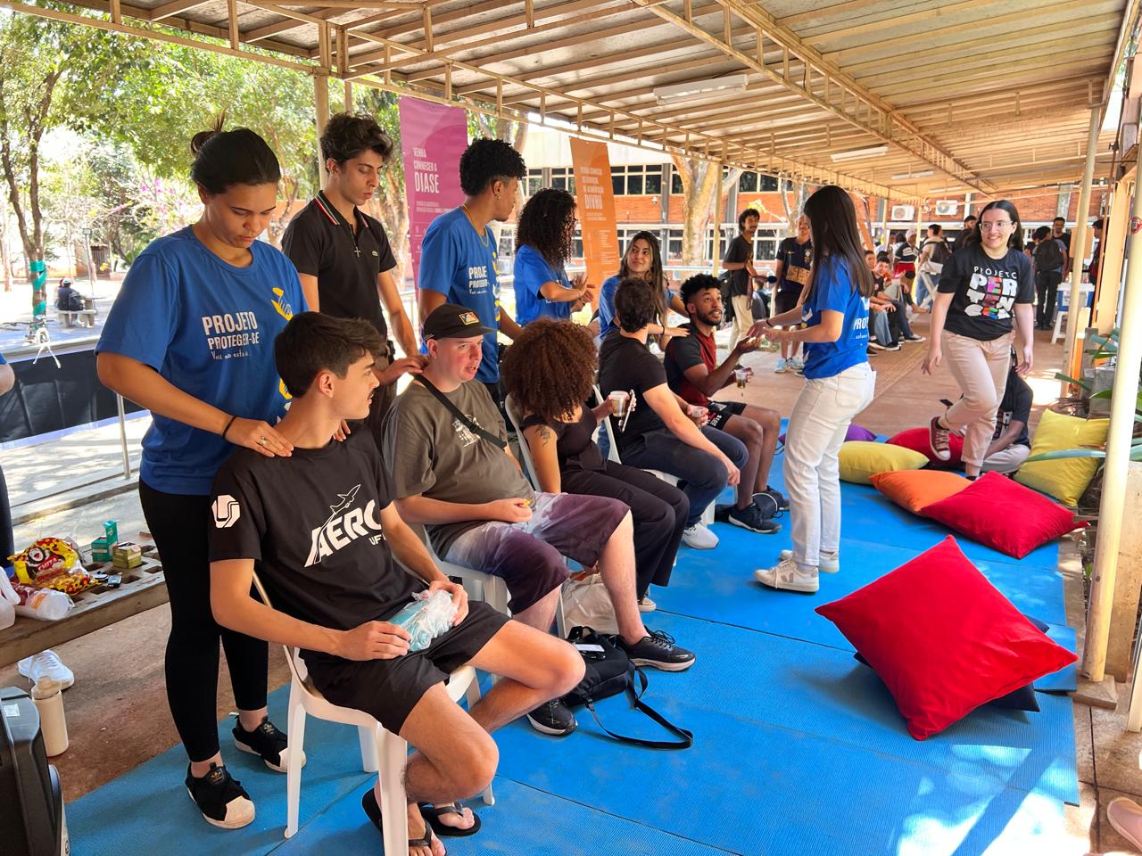 Imagem de ação do projeto, com um grupo sentado, sendo atendido por pessoas que estão em pé