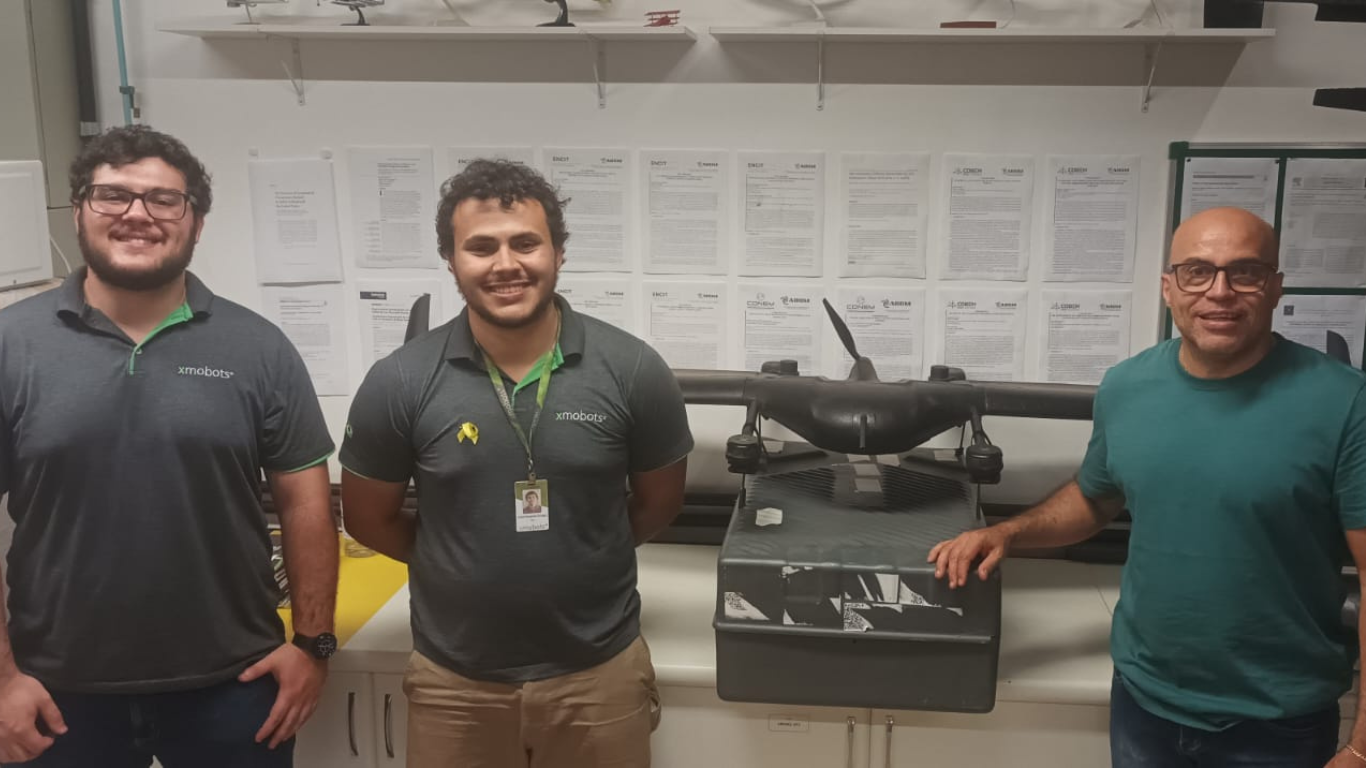 Professor Odenir e representantes da XMOBOTS em frente a uma hélice.