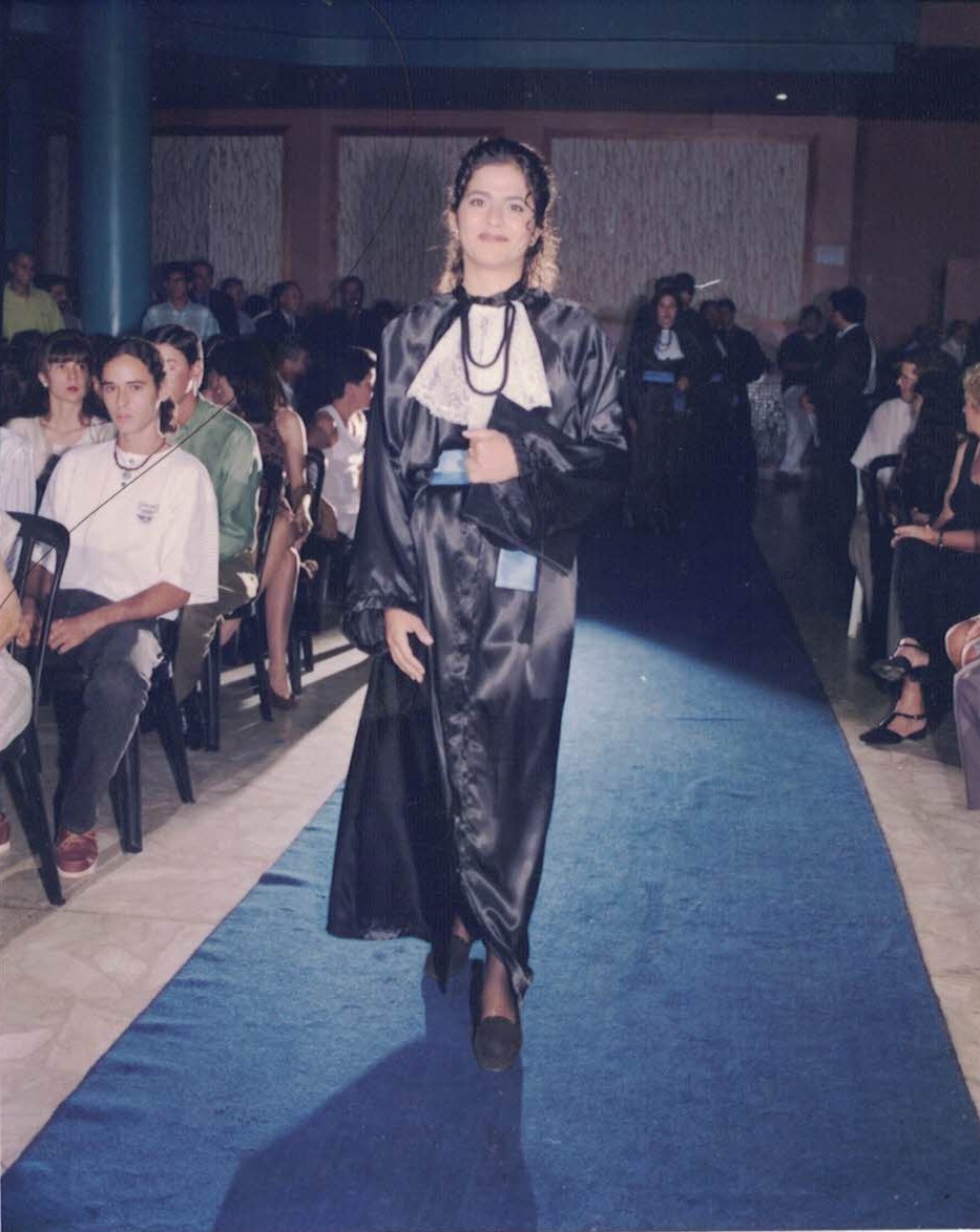 Imagem de Márcia Freire, vestida de beca, entrando numa solenidade de formatura