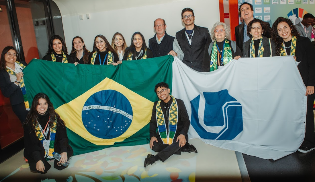 Foto de grupo da Enactus UFU posando com as bandeiras do Brasil e da universidade