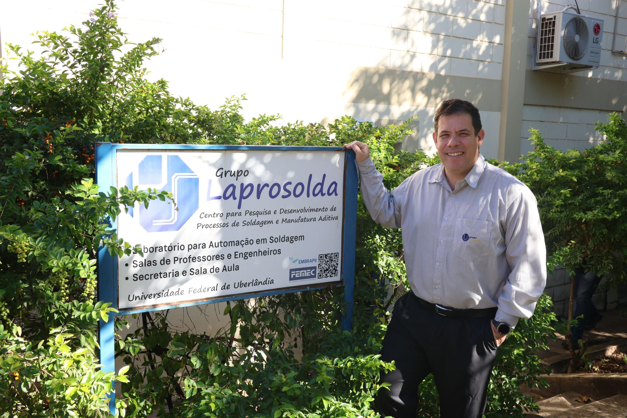 Professor Vilarinho ao lado da placa do laboratório.