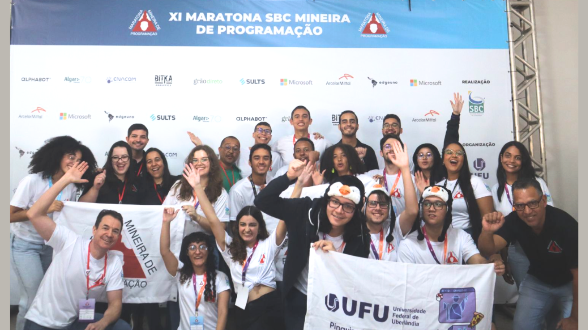 Foto dos estudantes de Computação da UFU, em frente ao banner da Maratona Mineira de Programação