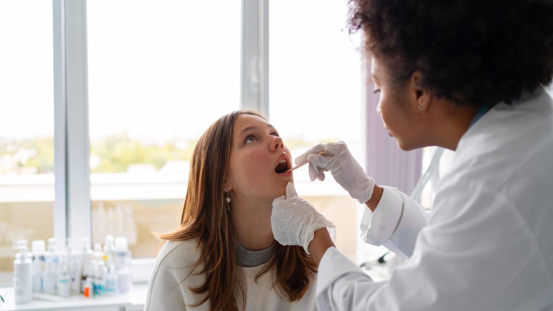 Mulher profissional de saúde colhendo amostra salivar de paciente mulher