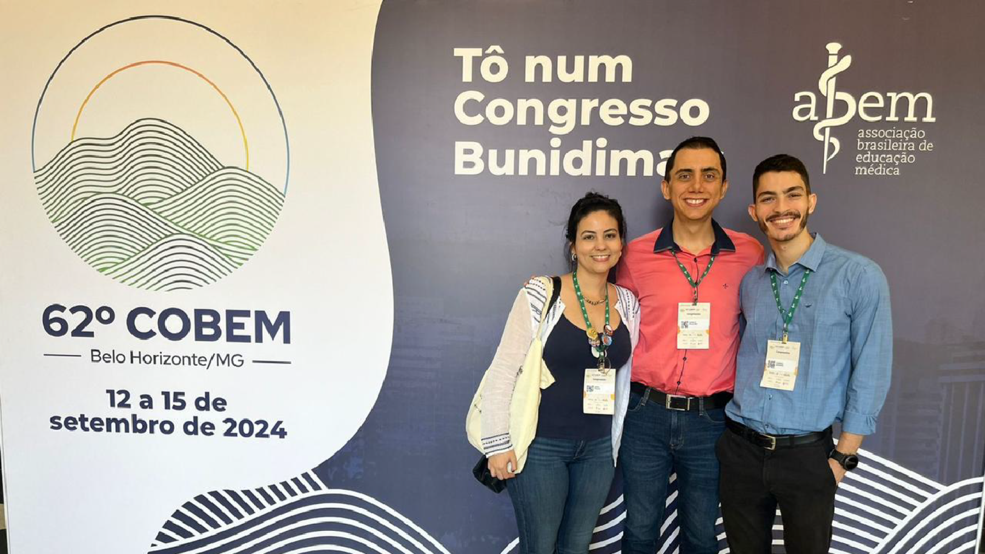 O professor, Danilo Paulino, e dois petianos em frente ao backdrop do evento.