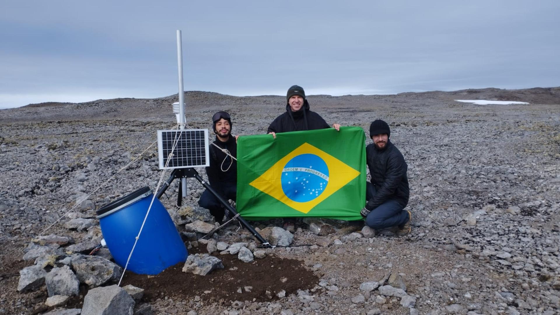 Pesquisadores segurando a bandeira do Brasil na Antártida