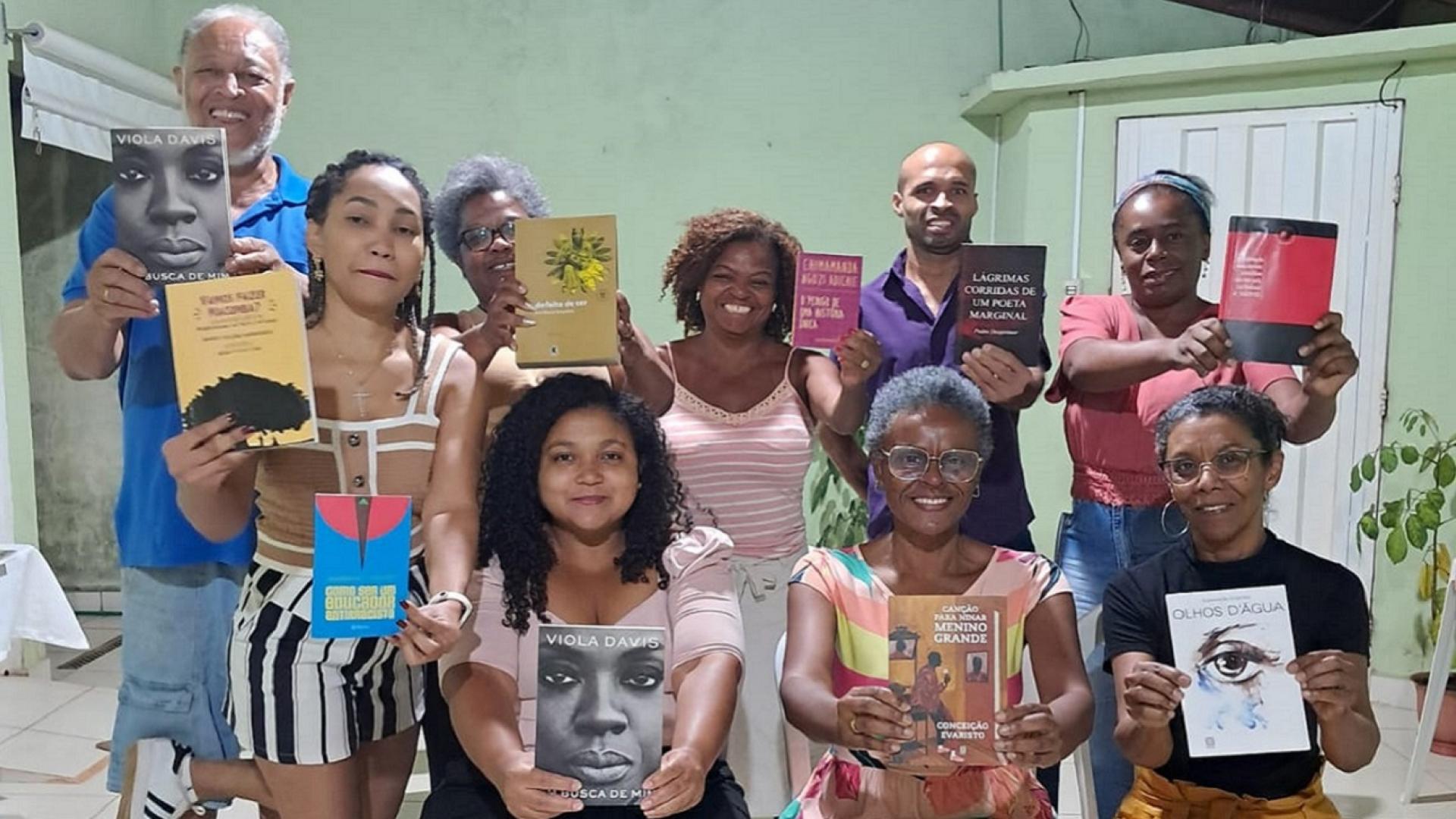 Grupo com pessoas exibindo livros de autores negros; são 2 homens e 7 mulheres