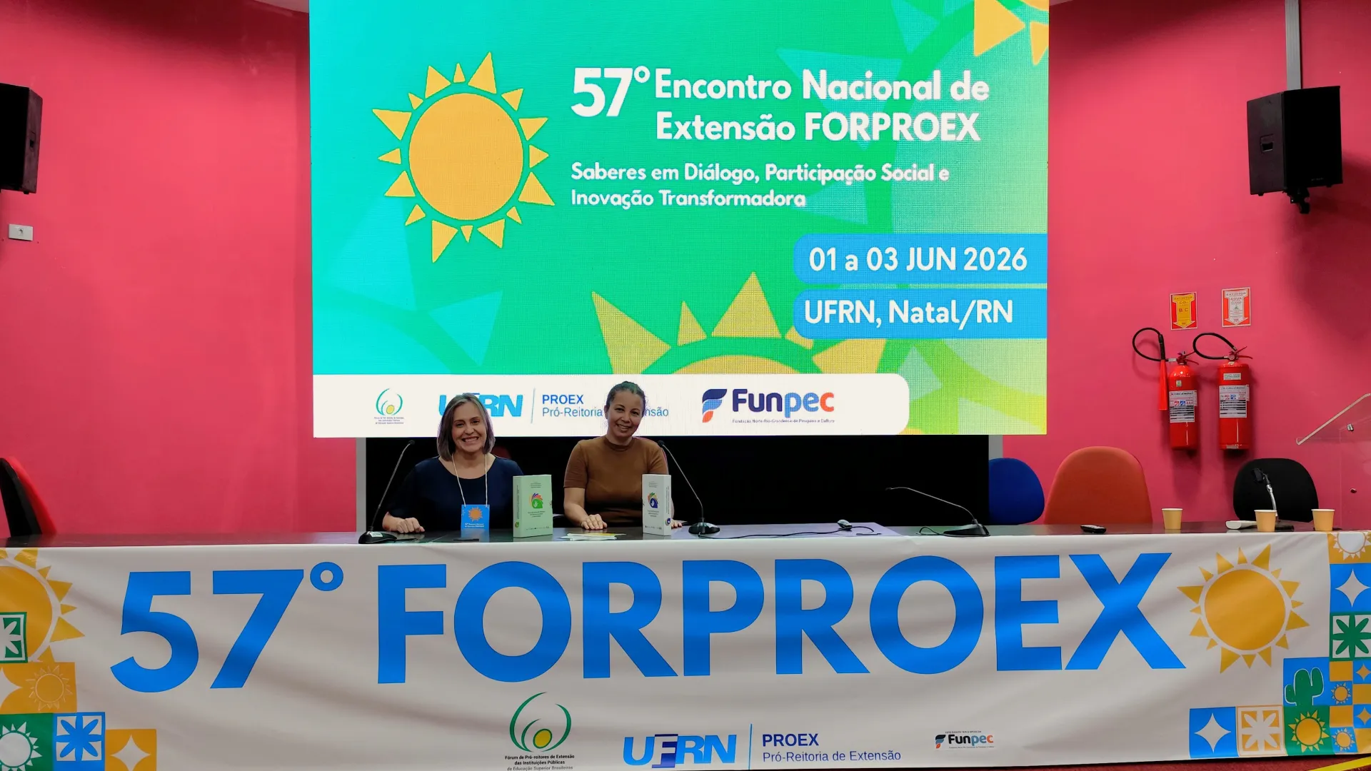 Foto de Valéria Rodrigues e Gláucia Carvalho, sentadas à mesa do 57º FORPROEX