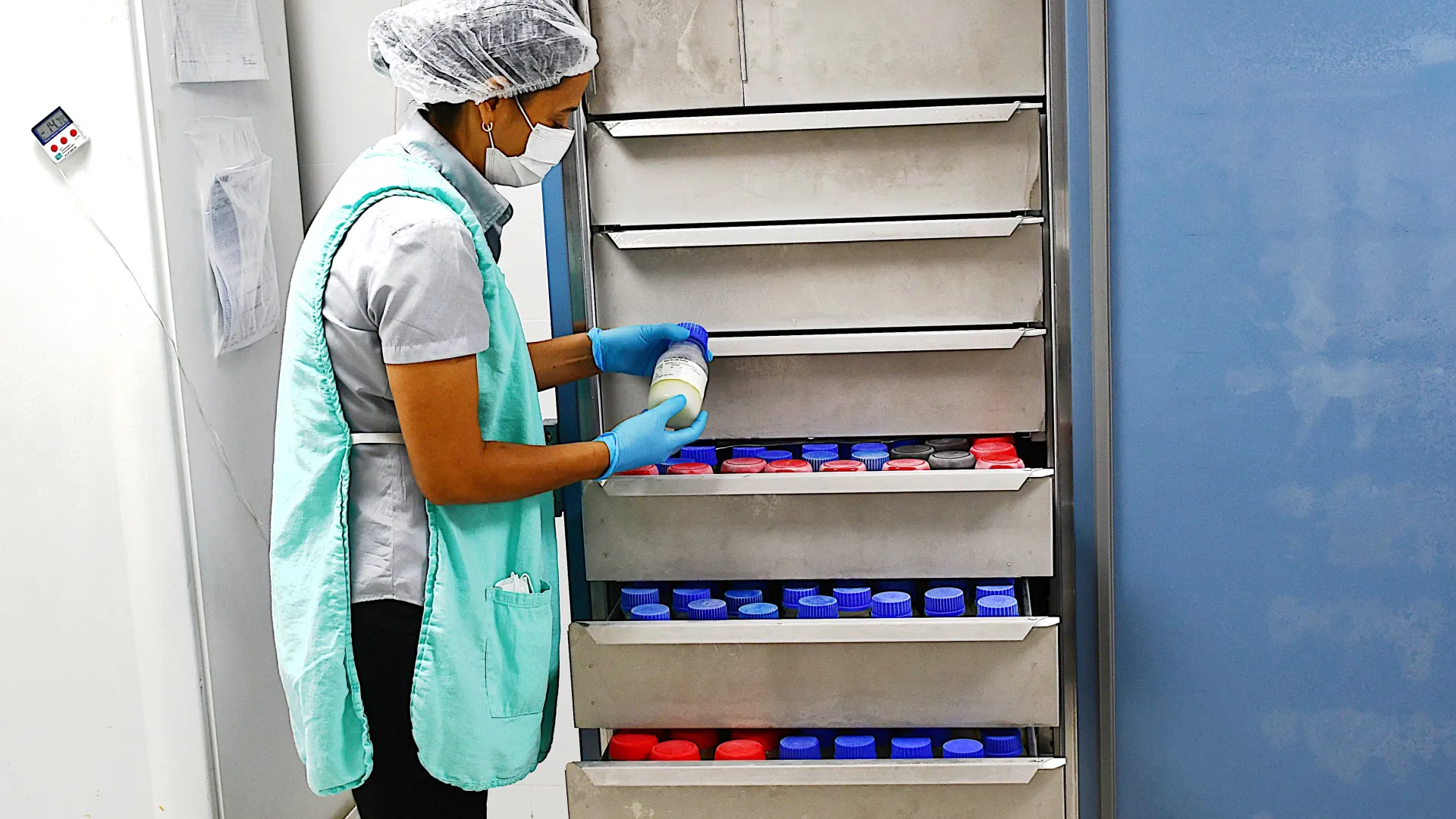 Enfermeira coletando leite humano de uma geladeira de armazenamento. (Foto: Milton Santos)
