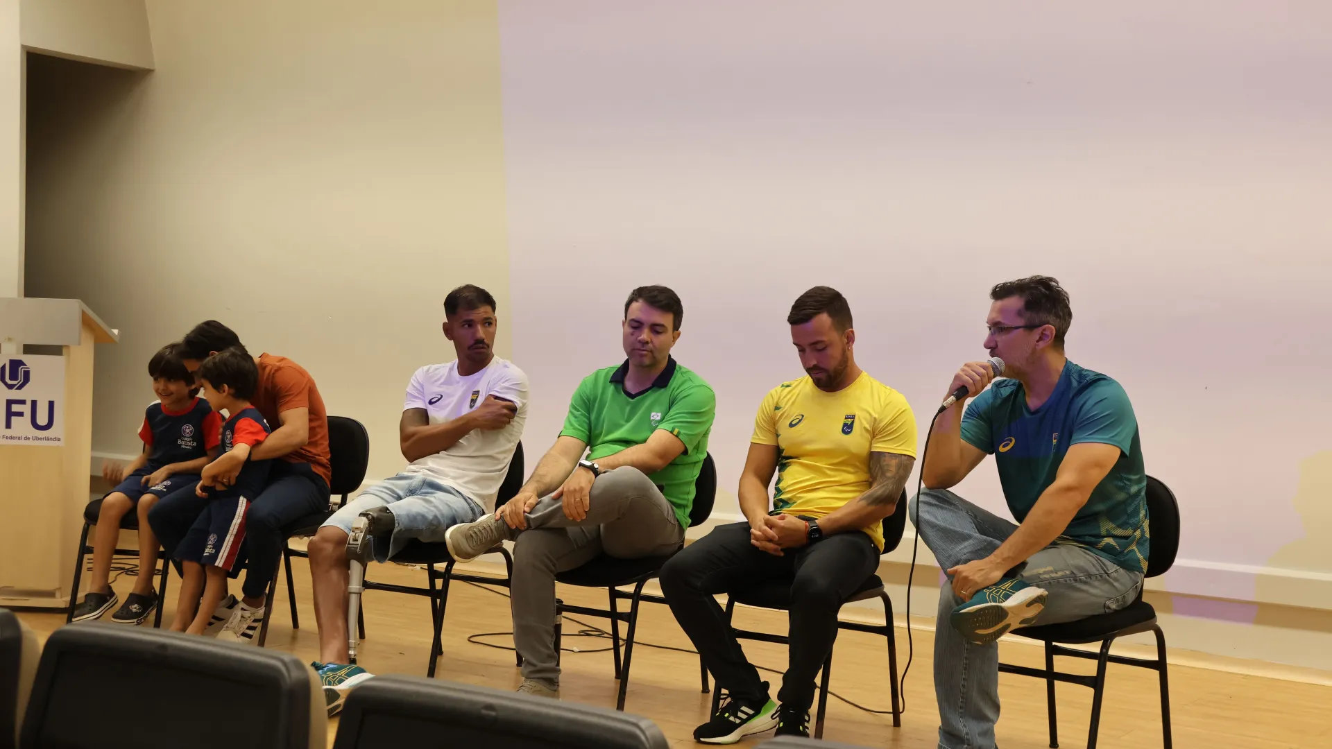 Membros da mesa-redonda sentados em cadeiras no palco do anfiteatro