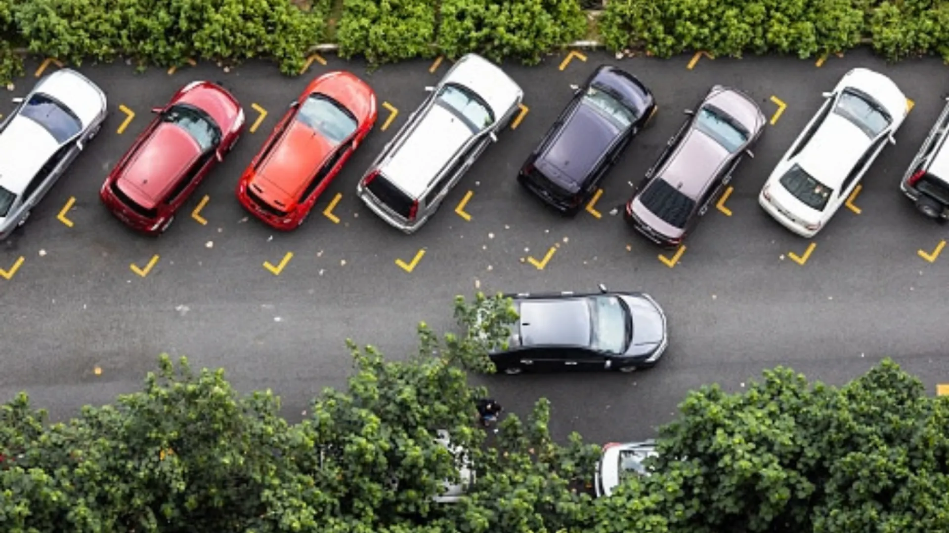 Estacionamento diagonal sem vagas disponíveis e um carro andando na rua ao lado.