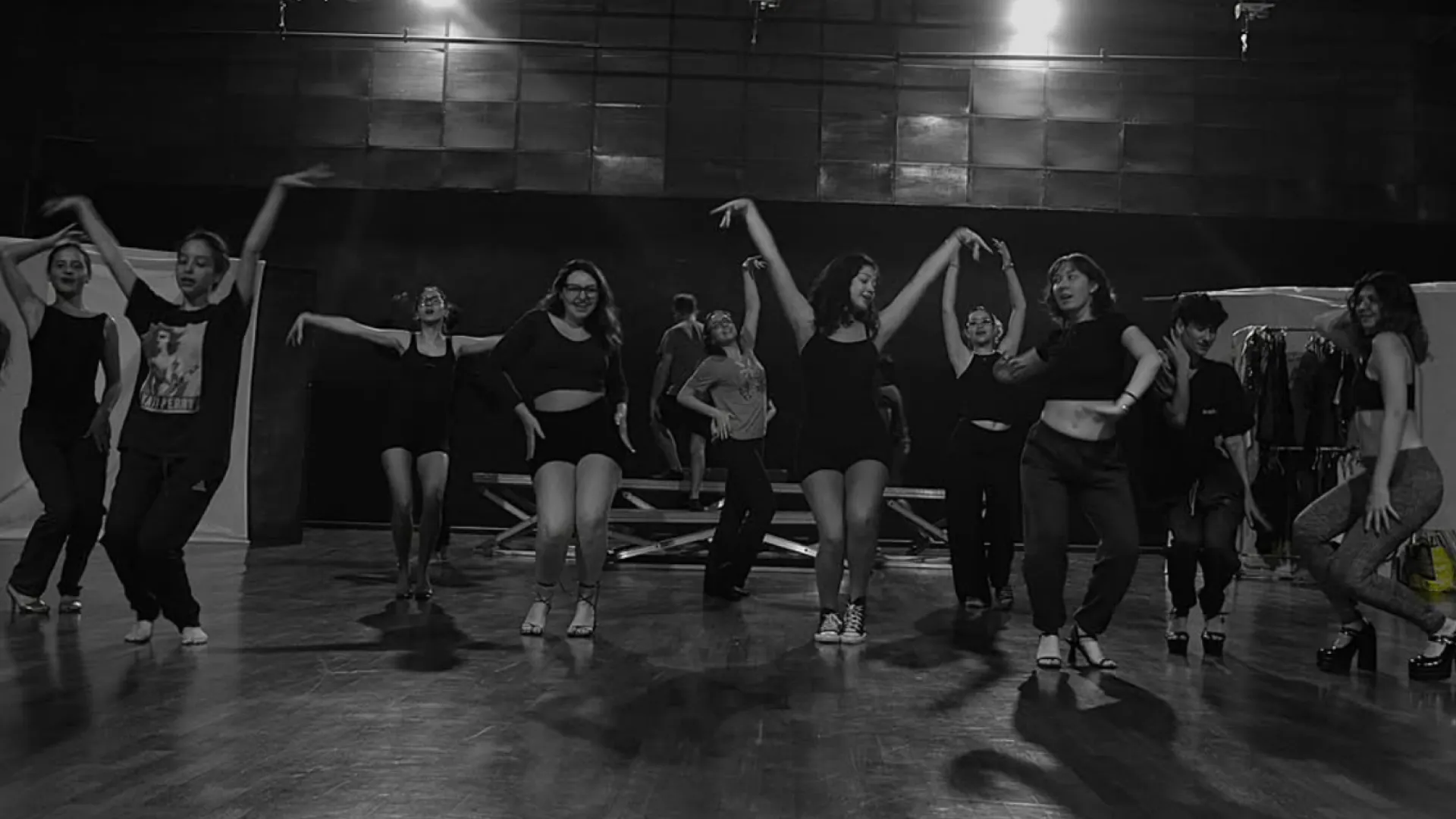 Fotografia em preto e branco, com grupo de estudantes do curso de Teatro da UFU dançando em um palco
