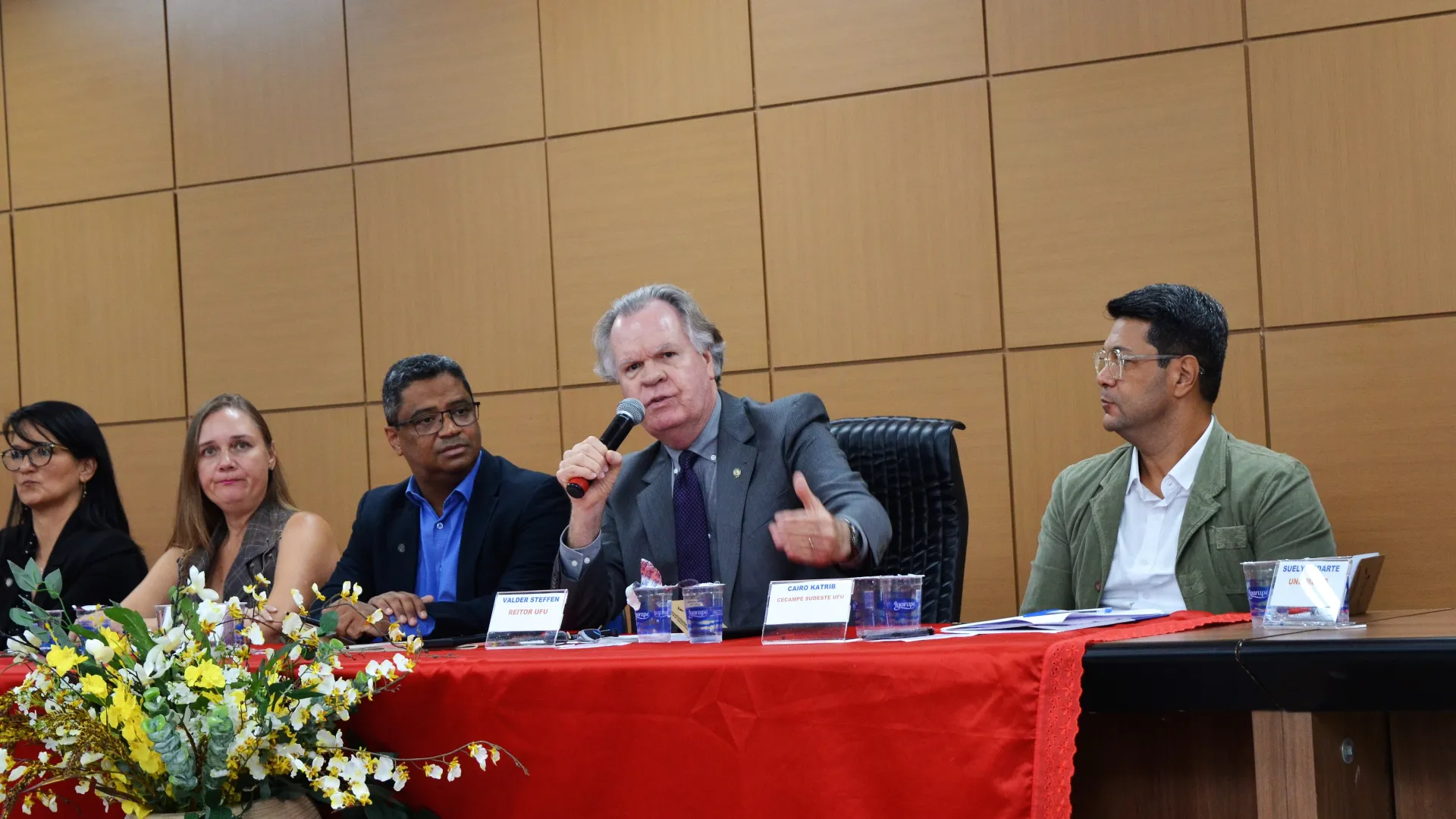 Reitor da UFU, Valder Steffen Junior, sentado e falando com o microfone na mão
