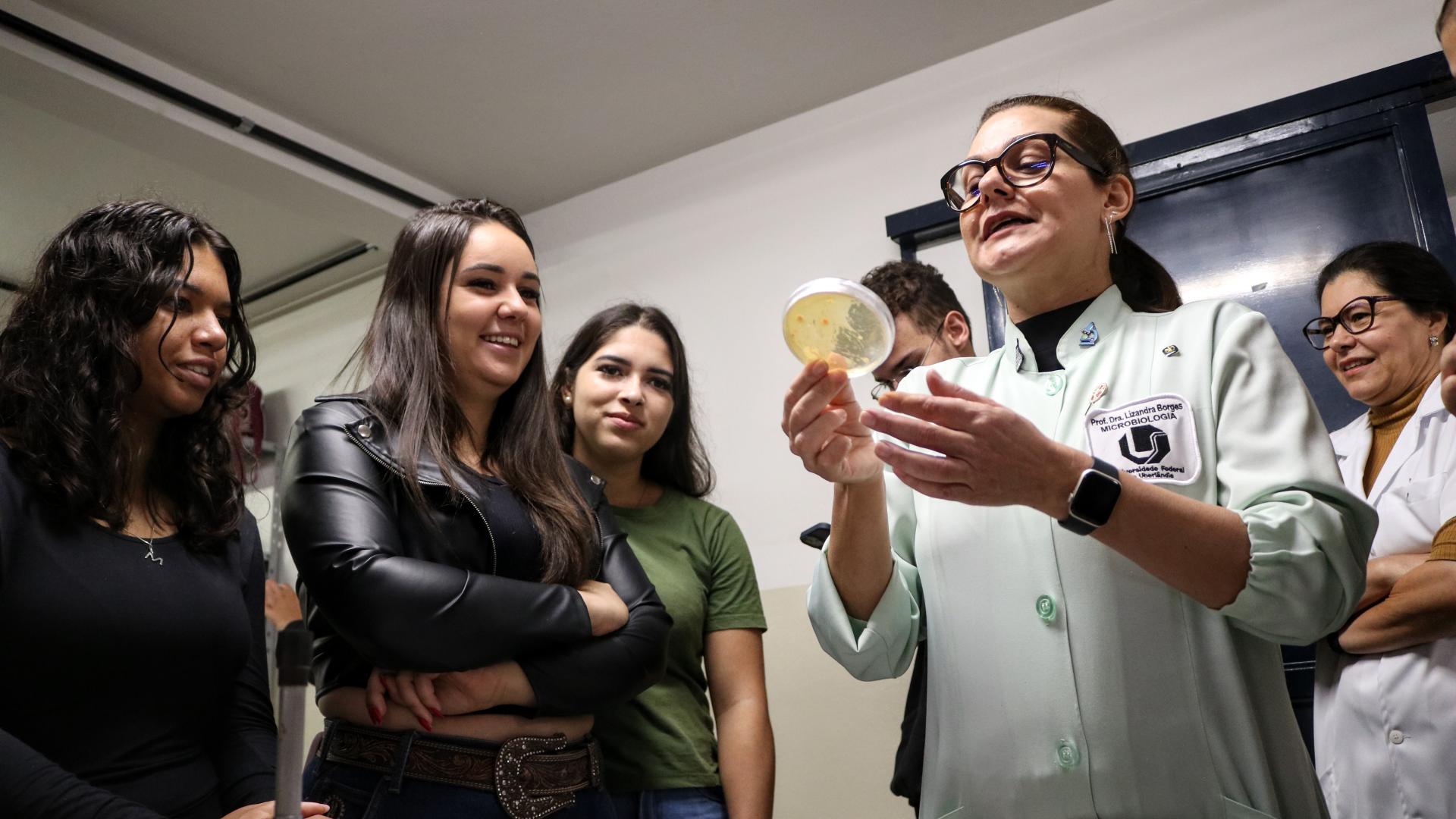 Lizandra com uma plaquinha com bactérias em mãos