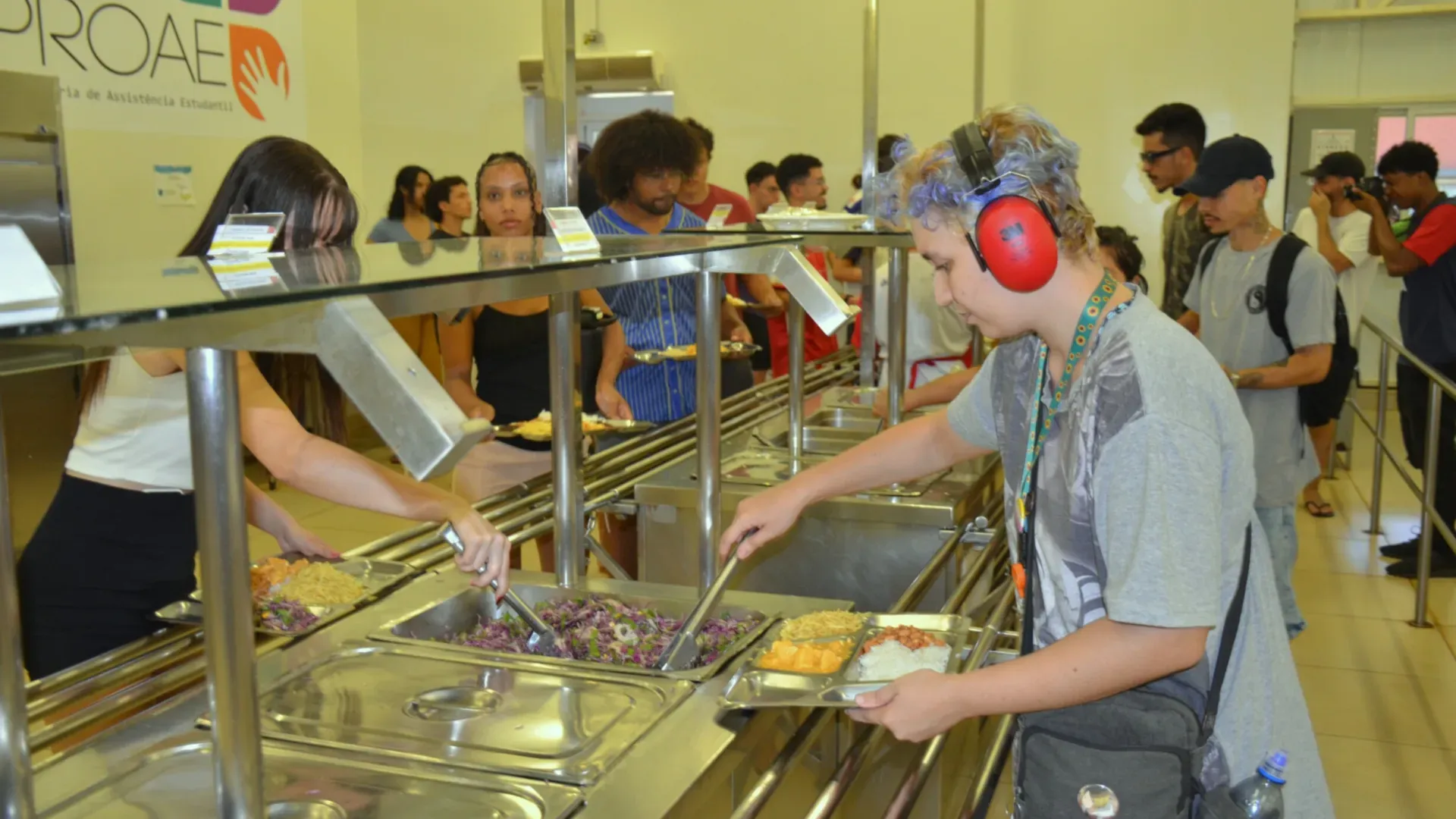 Estudante colocando comida na bandeja de refeição