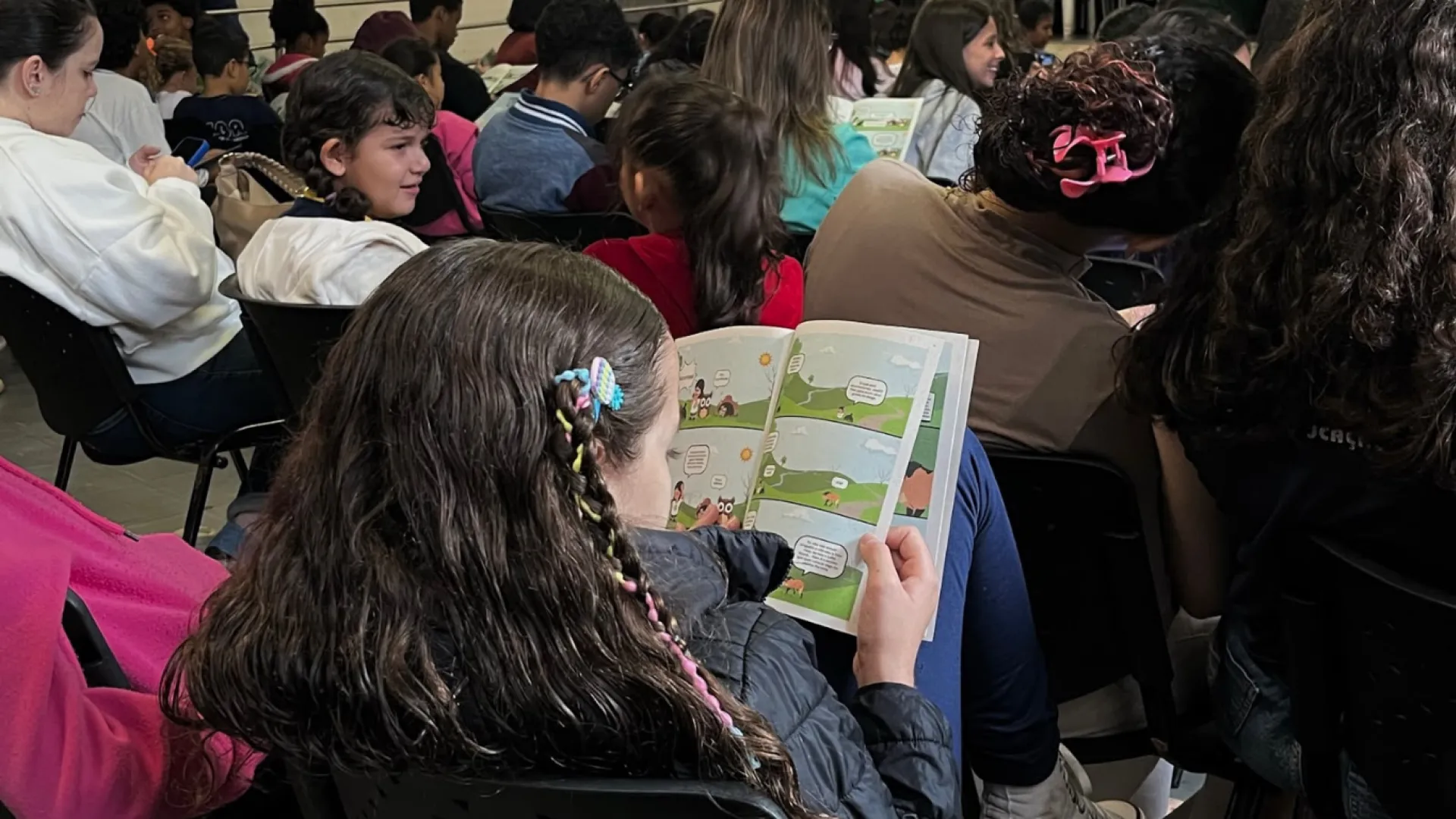 Menina lendo o livreto distribuído