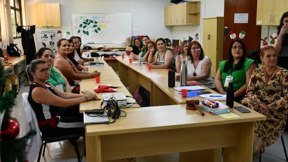 Na mesa é possível ver os participantes do projeto, que assistem à encenação de seus colegas