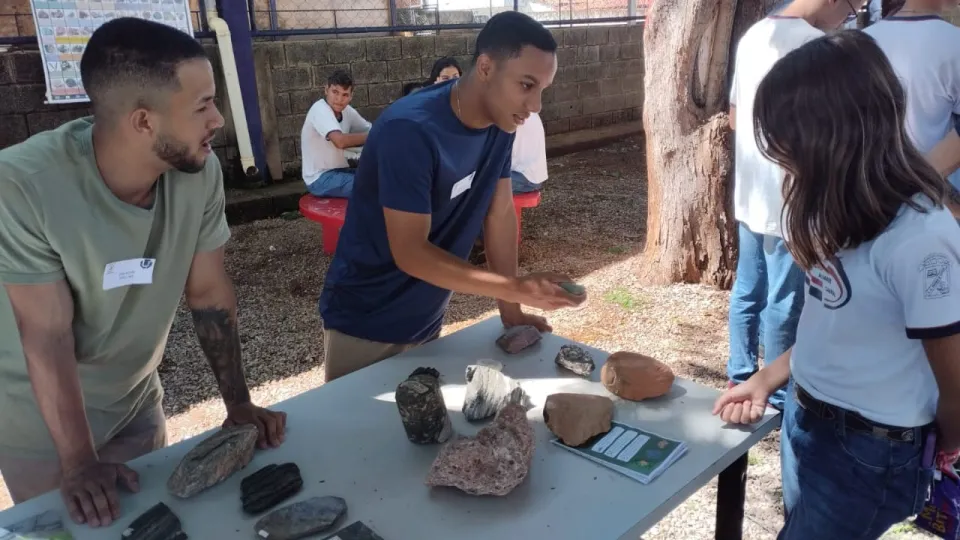 Estudante da UFU segurando rocha e falando com aluna do ensino médio