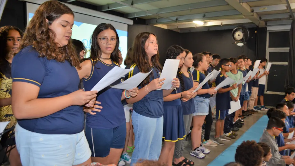 Há um grupo de crianças uniformizadas cantando