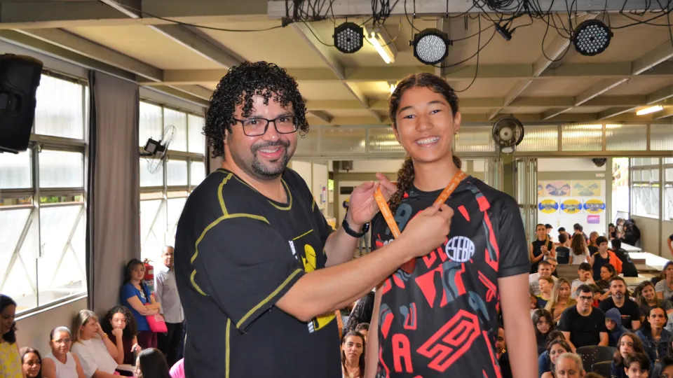 Um homem entrega uma medalha para uma garota