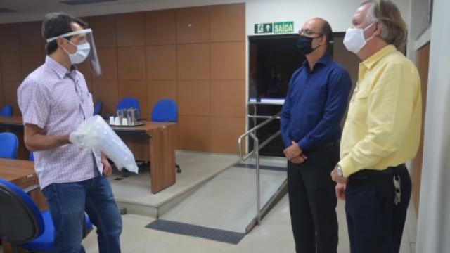 Fernando Souza faz a entrega dos protetores faciais aos gestores da UFU, Valder Steffen, e do HC, Nilton Pereira