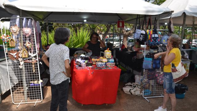 Barraca de artesanato com mulheres escolhendo seus produtos.