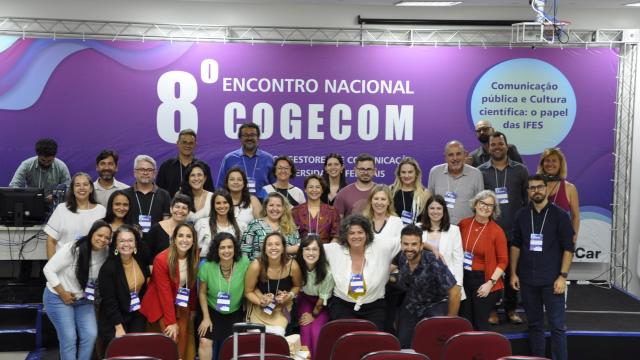 Participantes do 8º Congresso Nacional Cogecom posam em frente ao backdrop do evento