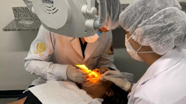 A imagem mostra duas profissionais de odontologia fazendo atendimento a paciente