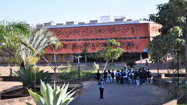 Vista aberta de estudantes transitando pelo Campus Santa Mônica da UFU, em Uberlândia, próximo ao bloco da Biblioteca