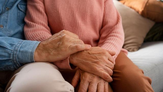 Foto mostra braços dados de duas pessoas idosas