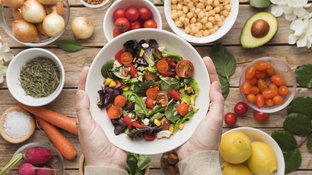 Vista superior de ingredientes e legumes em um prato de salada. Em volta, estão pequenas vasilhas com alimentos deste contexto