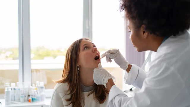 Mulher profissional de saúde colhendo amostra salivar de paciente mulher