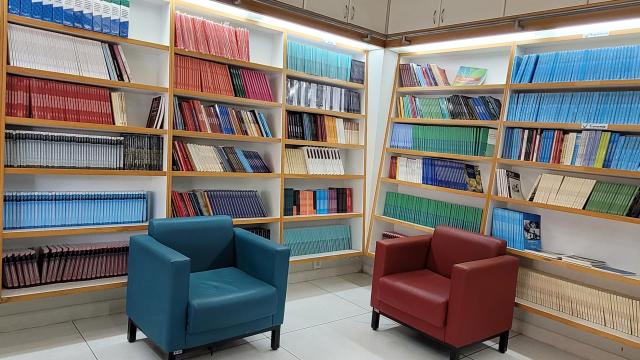 Poltronas posicionadas próximas às prateleiras, na livraria da Edufu