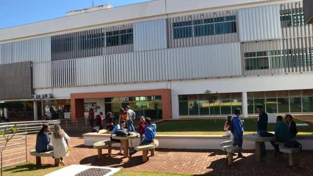 Estudantes sentados e em pé interagindo no espaço de convívio ao ar livre do Campus Pontal da UFU