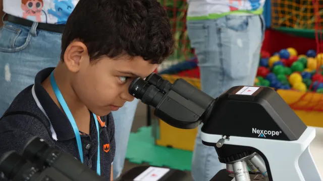 Criança olhando no microscópio