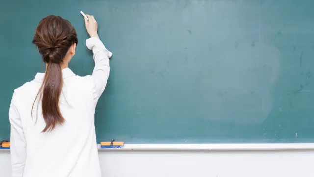 Professora escreve no quadro da sala de aula