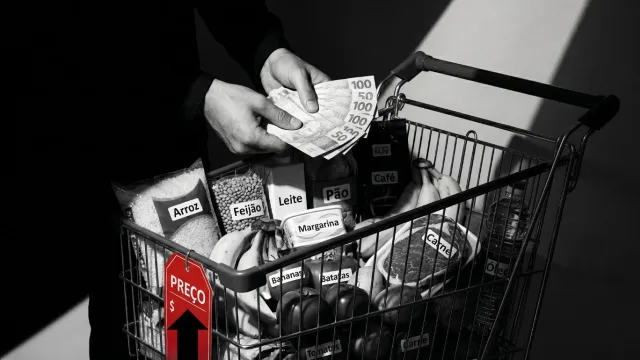 Homem segura dinheiro próximo ao carrinho de compras com itens da cesta básica