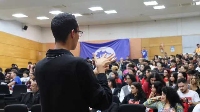 Interprete de libras de costas para a foto e de frente para o auditório do bloco 3Q da UFU lotado