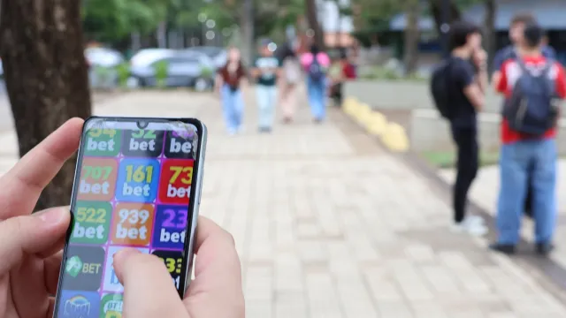 Jovem aposta no celular na universidade